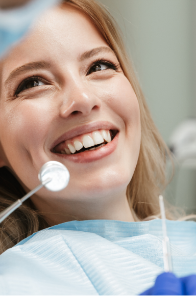 Female dental patient smiling up at her dentist in Fredericksburg