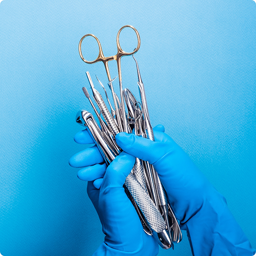 Gloved hands holding multiple dental instruments